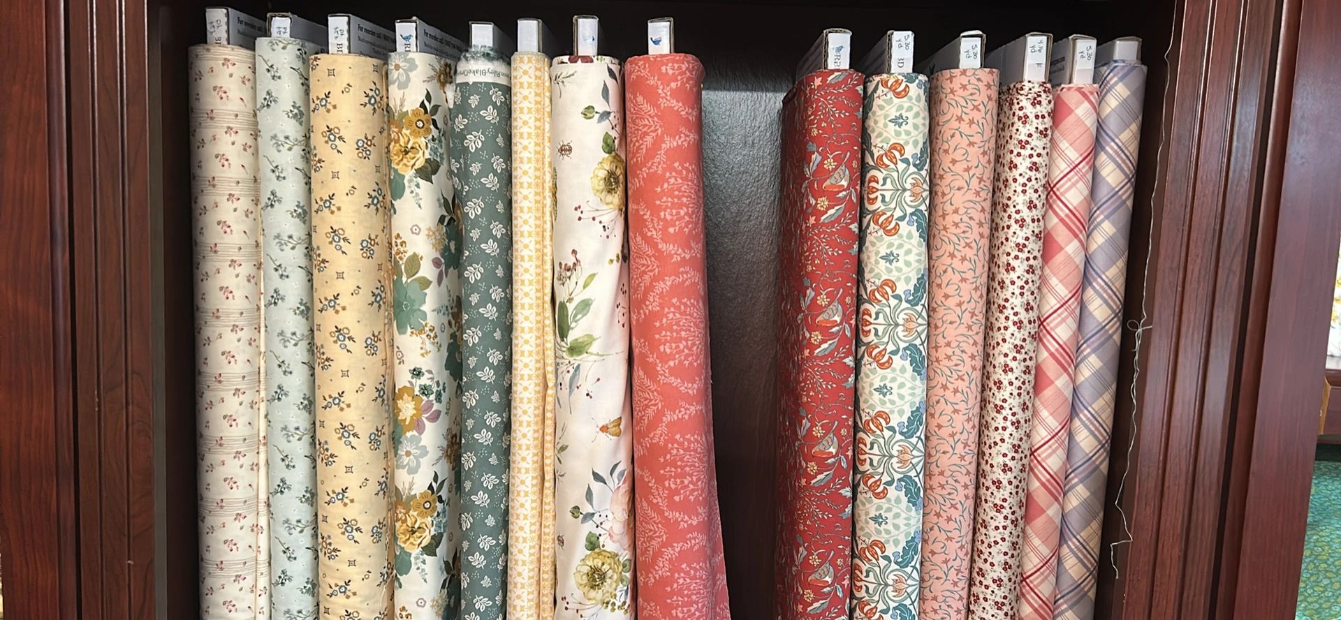 Fabric bolts displayed on shelves in the shop